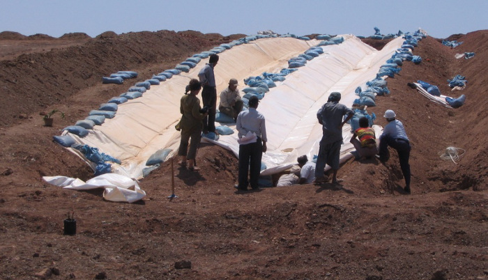 Installation utilisant des bâches de plastique amarrées par des sacs de terre, pour éviter que le vent les bousculent, à Panandhro, Inde .  JPEG - 123.8 ko